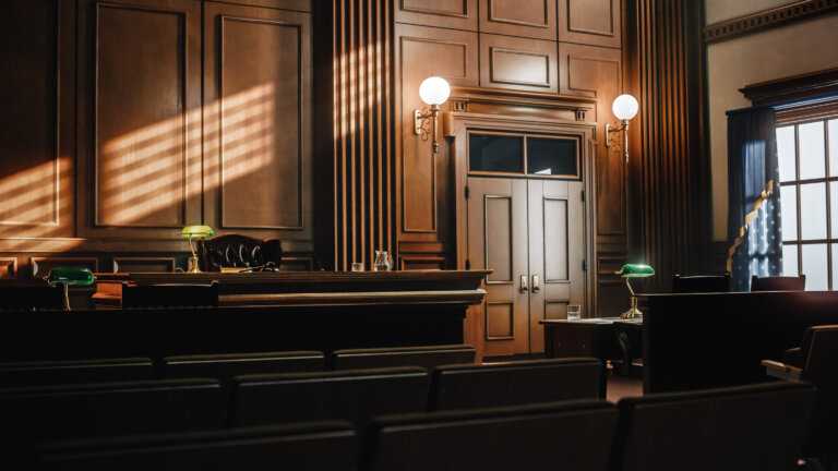 empty courtroom with wooden paneling and judge’s bench