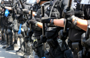 Police with batons forming a line during a public disturbance