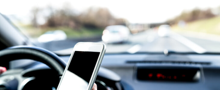 Female driver texting on mobile phone while driving.