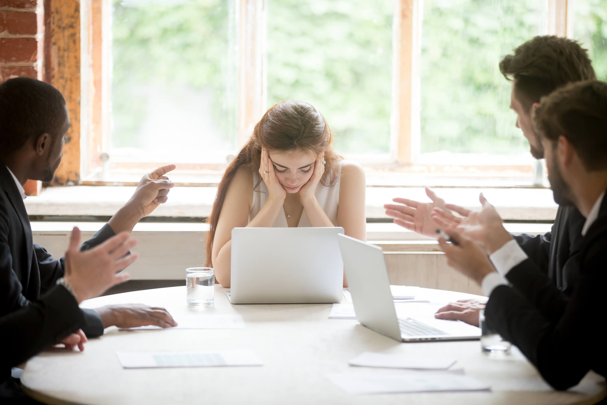Male colleagues pointing fingers at upset female boss on meeting, tired sad woman leader experiencing gender discrimination at work, businessmen blaming bullying depressed businesswoman for mistake