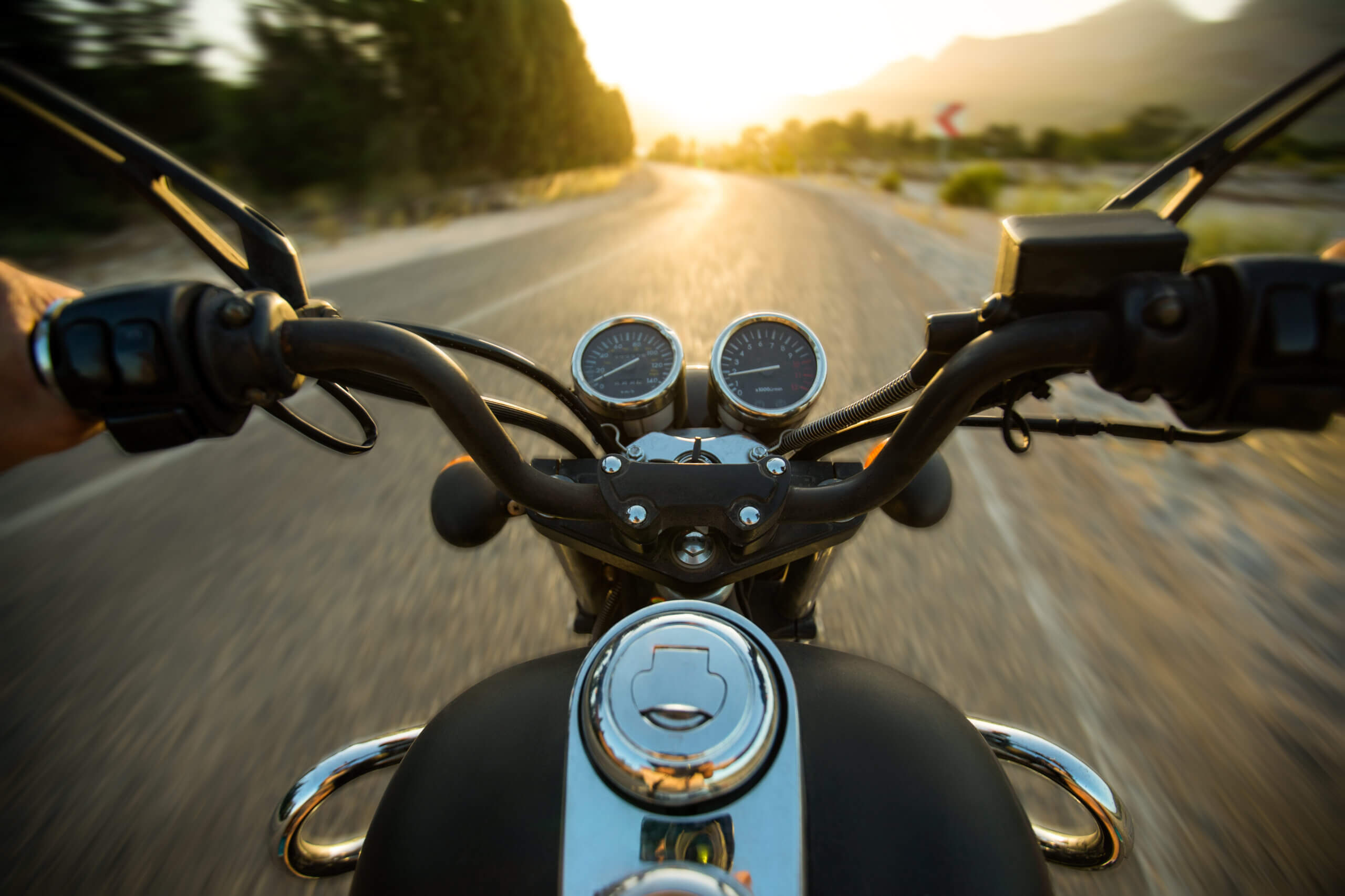 motorcycle handlebars view on open road at sunset