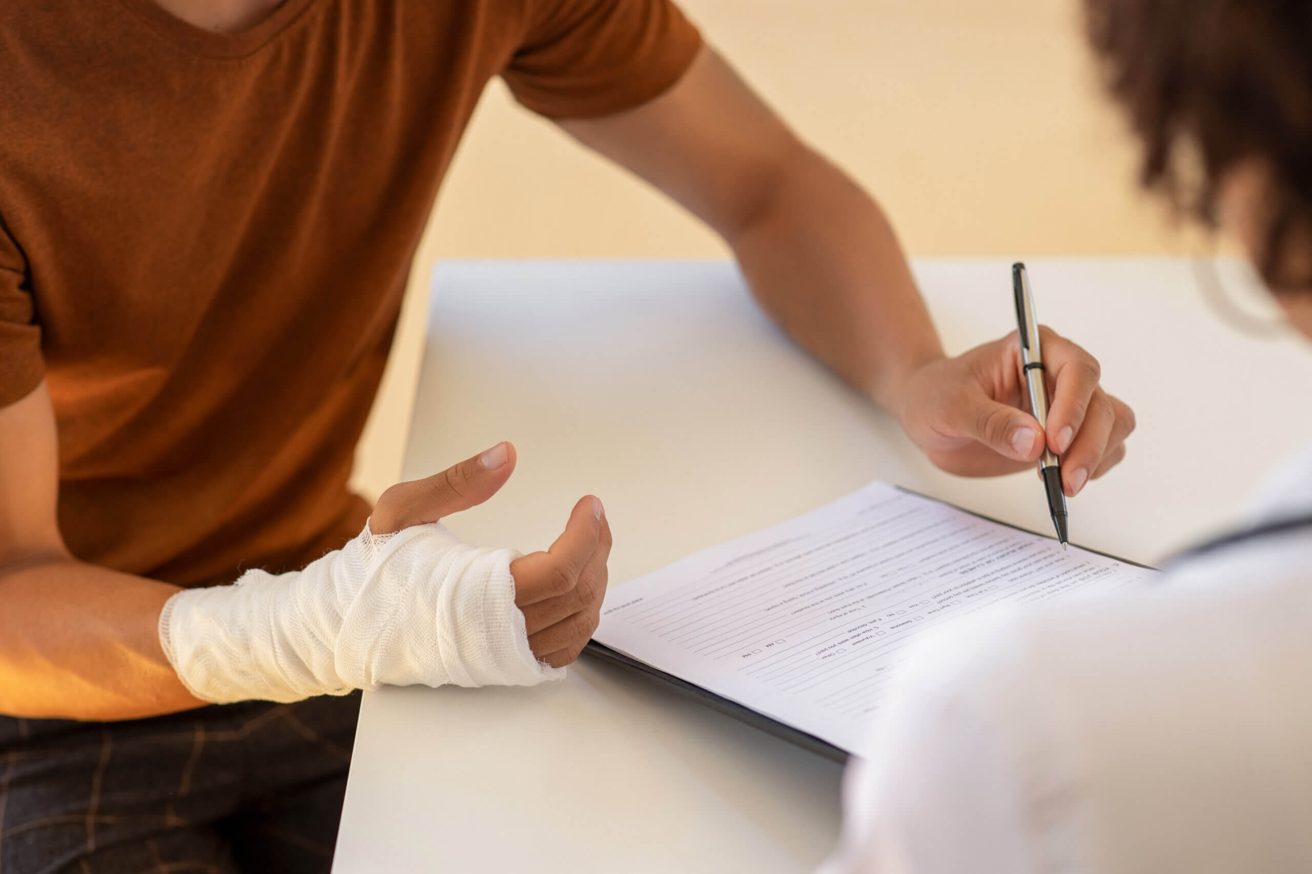 injured person with bandaged hand reviewing paperwork with professional
