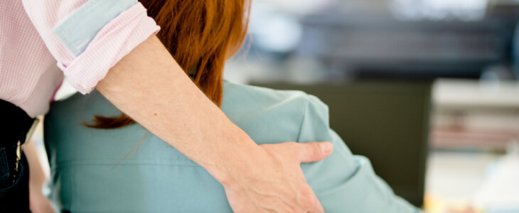 hand on woman’s shoulder at work