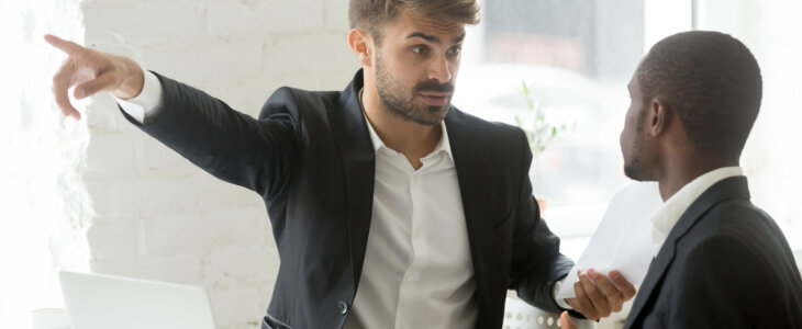 Angry rude caucasian executive firing male incompetent african employee for bad work, impolite white partner telling black businessman to get out detecting fraud, prejudice and racial discrimination